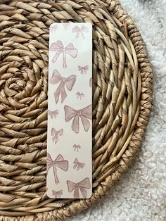 a bookmark with bows on it sitting in a wicker basket next to a woven place mat