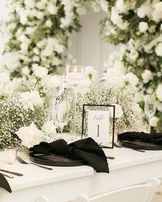 the table is set with black and white flowers, candles, and place settings for an elegant dinner