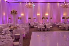 a banquet hall with tables, chairs and chandeliers set up for a formal function