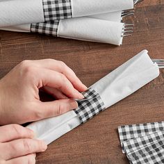 the person is making napkins with black and white checkered fabric on them,