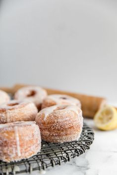 several glazed donuts on a cooling rack with lemon wedges next to them,