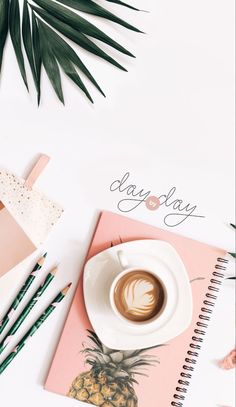 a cup of coffee on top of a pink notebook