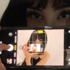 a woman holding up a cell phone to take a photo with her face on the screen