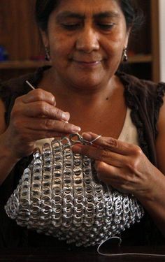 a woman is working on an object with metal wire and scissors in her hands while sitting at a table