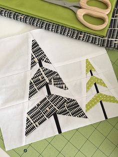 a pair of scissors sitting on top of a piece of fabric next to a cutting board