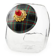 a glass vase with a red brooch in it's center and tartan plaid pattern