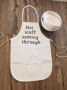 a white apron that says hot stuff coming through on the floor next to a measuring cup