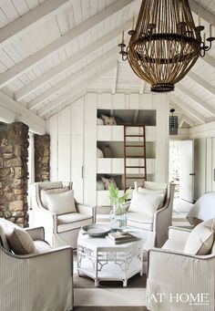 a living room filled with white furniture and a chandelier hanging from the ceiling