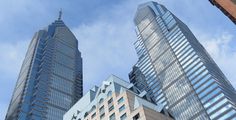 two very tall buildings next to each other under a blue sky with clouds in the background