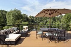 an outdoor patio with furniture and umbrellas on the wooden decking area overlooking trees