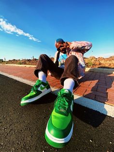 a man sitting on the ground next to a green shoe