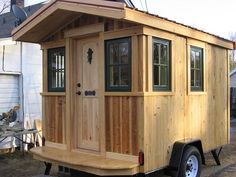 a small wooden house on wheels in the yard