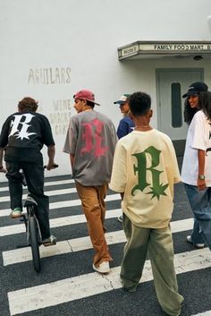 several people are walking and riding bikes in front of a building with the letters f on it