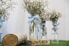 three glass vases filled with baby's breath flowers on top of a green field