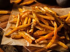 some french fries are sitting on a piece of wax paper next to other food items