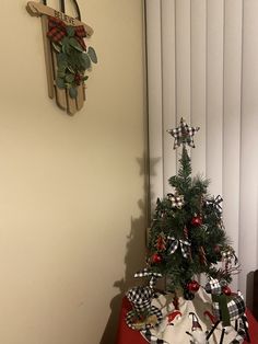 a small christmas tree sitting on top of a red table next to a white wall