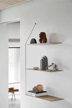 three shelves with various objects on them in a white room, one has a lamp and the other is a chair