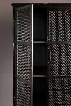 an open metal cabinet sitting on top of a wooden floor next to a gray wall