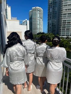 the bridesmaids are wearing silver robes and standing on a balcony with their backs to the camera