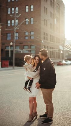 a man, woman and child standing in the middle of an empty street with buildings behind them