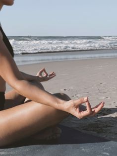 a woman sitting on the beach doing yoga