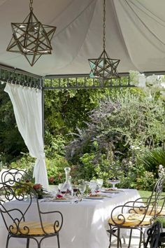 an outdoor dining area with white table cloths and chairs under a tented canopy