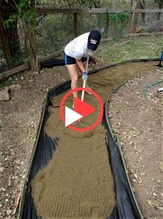 a woman is shoveling dirt into a garden bed with a black tarp over it