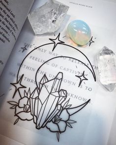 an open book with crystals on it and a crystal ball in the middle next to it