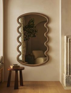 a mirror that is on the wall near a table with a potted plant in it