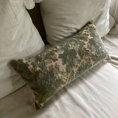 a bed with white sheets and pillows on top of it's headboard is shown