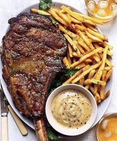 a steak and french fries on a plate with dipping sauces next to it,