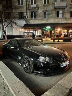 a black car parked in front of a building on the side of a street at night