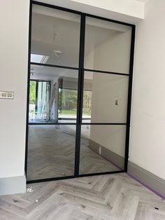 an empty room with glass doors and wood flooring in the middle, is shown