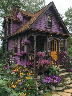 a purple house with lots of flowers around it