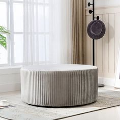 a round ottoman sitting on top of a white rug