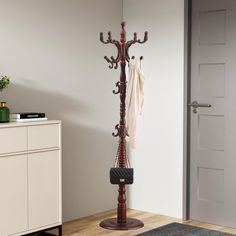 a coat rack with two coats hanging from it's sides and a purse on the floor