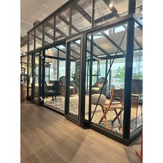 the inside of a building with glass walls and wooden flooring, chairs and tables