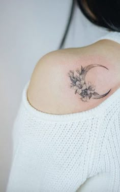 a woman's shoulder with a flower tattoo on the left side of her upper arm