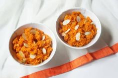 two bowls filled with carrots and almonds on top of a white table cloth