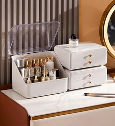 two white drawers with gold handles and lids on top of a table next to a mirror