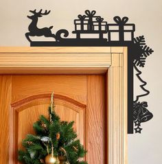 a christmas wreath on top of a wooden door next to a wall with reindeer and sleigh