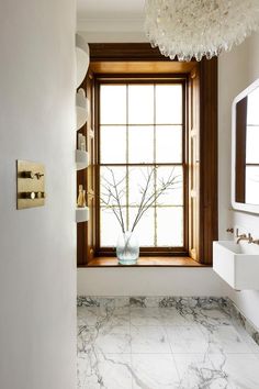 a bathroom with marble flooring and a large window in the corner that has a vase on it