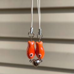 two orange bird shaped earrings hanging from hooks