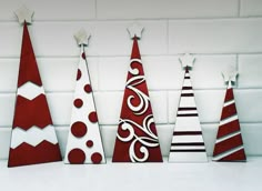 three red and white christmas trees on a shelf