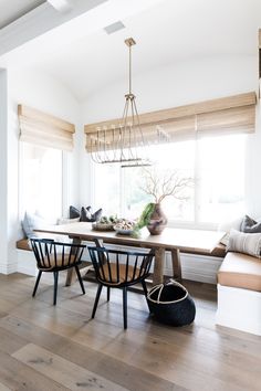 a dining room table with four chairs and a bench in front of the window,