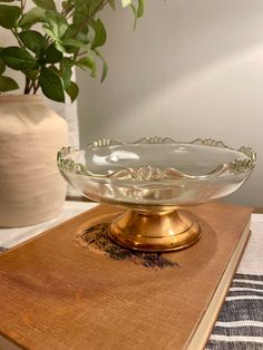 a glass bowl sitting on top of a wooden table next to a potted plant