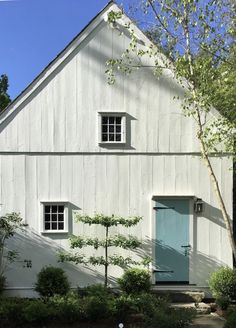 a white barn with a blue door and window on the side of it's building