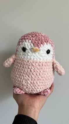 a hand holding a pink and white crocheted stuffed animal with an owl on it's face