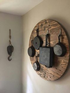 a wooden clock mounted to the side of a wall with pots and pans on it