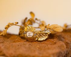 a close up of a gold ring with leaves on it and a diamond in the middle